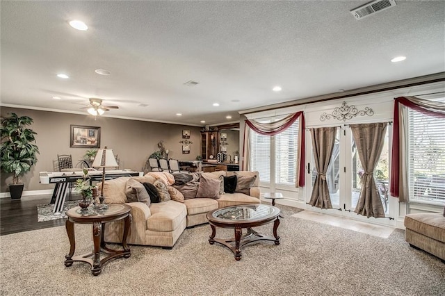 living area with a textured ceiling, visible vents, crown molding, and recessed lighting