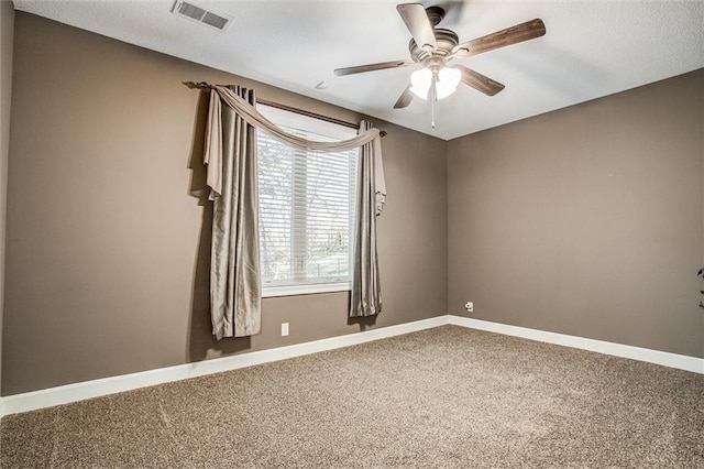 carpeted spare room with baseboards, visible vents, and a ceiling fan