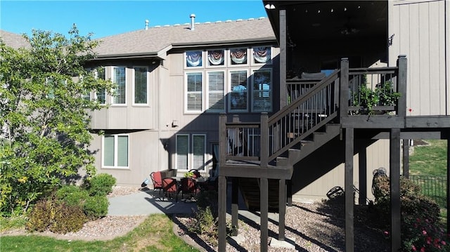 rear view of property featuring roof with shingles, a patio, a wooden deck, and stairs