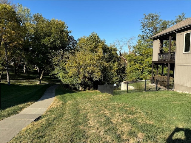 view of yard with a balcony and fence