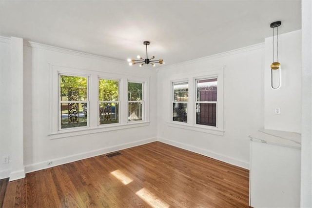 spare room featuring dark hardwood / wood-style floors, an inviting chandelier, and plenty of natural light