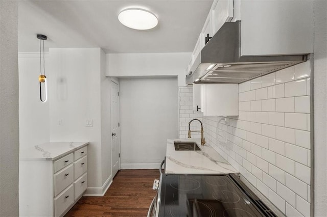 kitchen featuring dark wood-type flooring, white cabinetry, decorative light fixtures, and ventilation hood