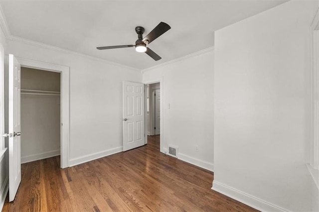 unfurnished bedroom featuring ornamental molding, dark hardwood / wood-style floors, a closet, and ceiling fan