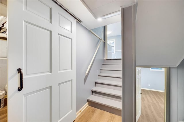 stairway featuring a healthy amount of sunlight and hardwood / wood-style flooring