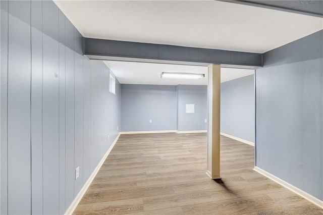 basement featuring light hardwood / wood-style flooring and wood walls