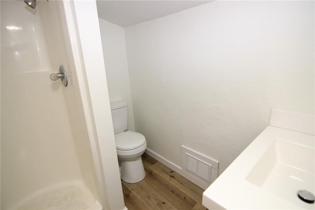 bathroom featuring walk in shower, sink, hardwood / wood-style floors, and toilet