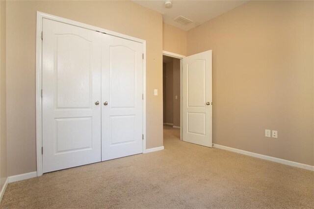 unfurnished bedroom featuring light colored carpet and a closet