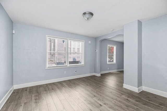 446 Montgall Ave, Kansas City, MO 64124 - empty room featuring wood finished floors, baseboards, and arched walkways