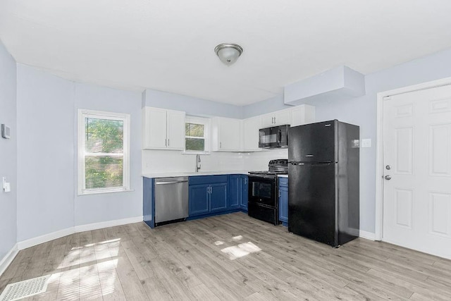 446 Montgall Ave, Kansas City, MO 64124 - kitchen featuring black appliances, blue cabinetry, light wood-style flooring, and light countertops