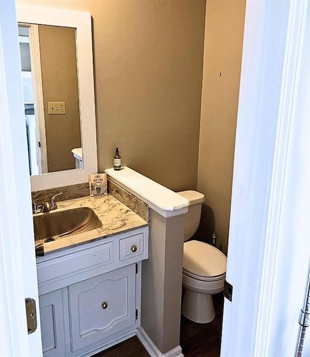 bathroom with hardwood / wood-style flooring, toilet, and vanity