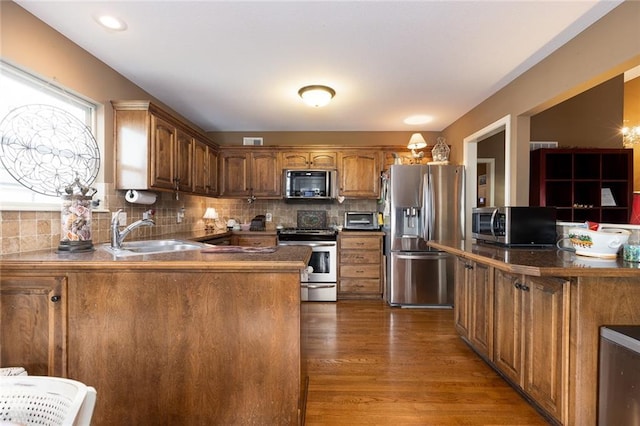 kitchen with tasteful backsplash, sink, appliances with stainless steel finishes, and dark wood-type flooring