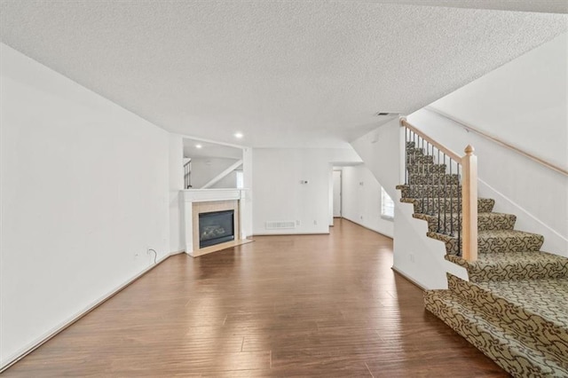 unfurnished living room with hardwood / wood-style flooring and a textured ceiling