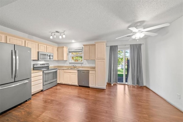 kitchen with ceiling fan, sink, hardwood / wood-style floors, a textured ceiling, and appliances with stainless steel finishes