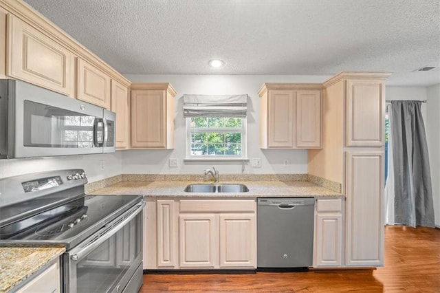 kitchen with sink, stainless steel appliances, a textured ceiling, and wood-type flooring