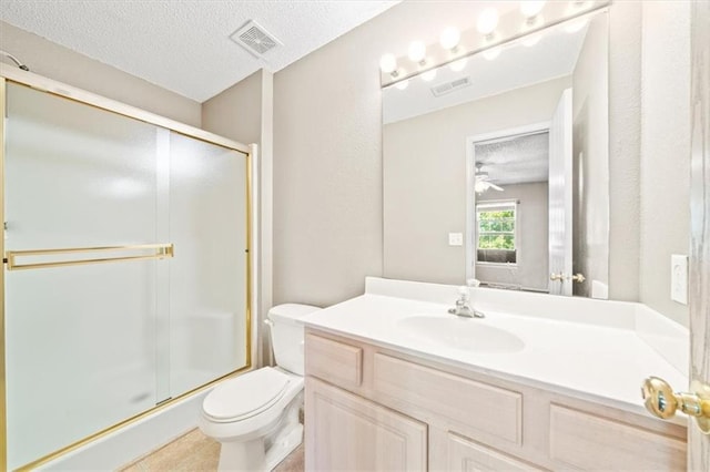 bathroom with vanity, toilet, a shower with door, and a textured ceiling