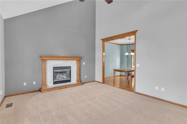 unfurnished living room featuring ornamental molding, vaulted ceiling, carpet flooring, and ceiling fan with notable chandelier