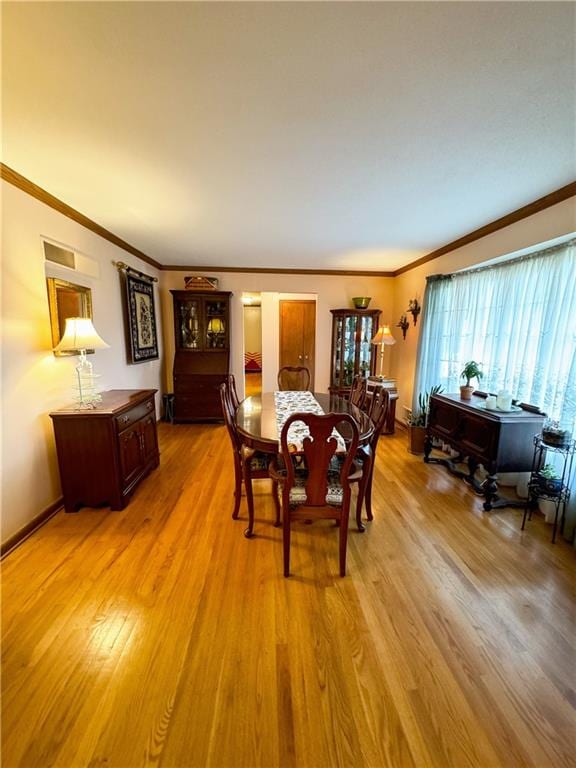 dining area with ornamental molding and light hardwood / wood-style flooring