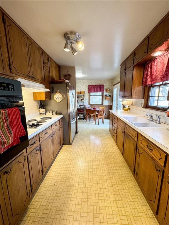 kitchen featuring white gas stovetop, backsplash, black oven, sink, and ceiling fan