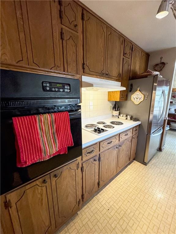 kitchen featuring tasteful backsplash, white gas cooktop, stainless steel refrigerator, and oven