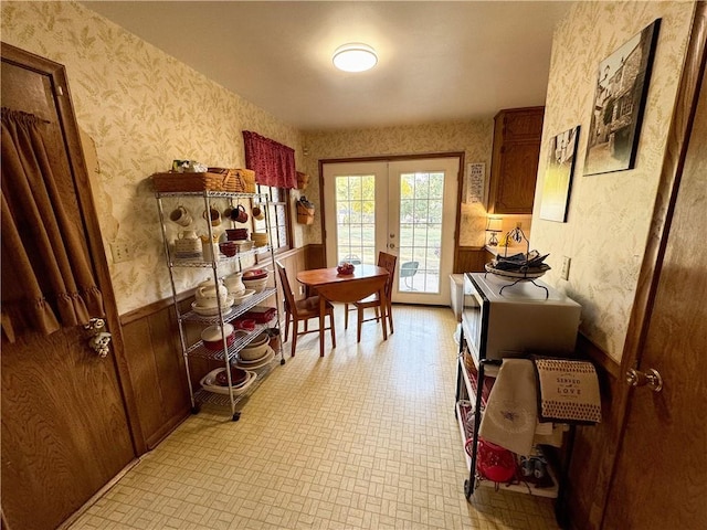 dining space with french doors and wood walls