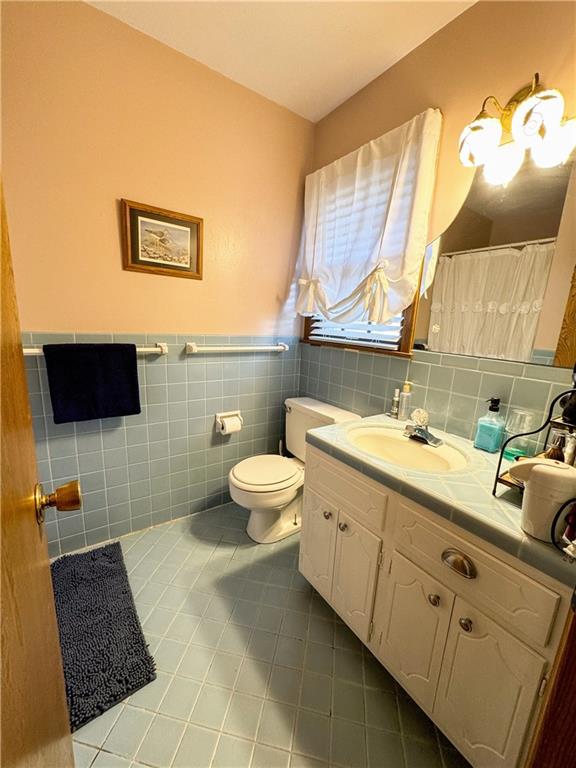 bathroom featuring toilet, vanity, tile walls, and tile patterned flooring