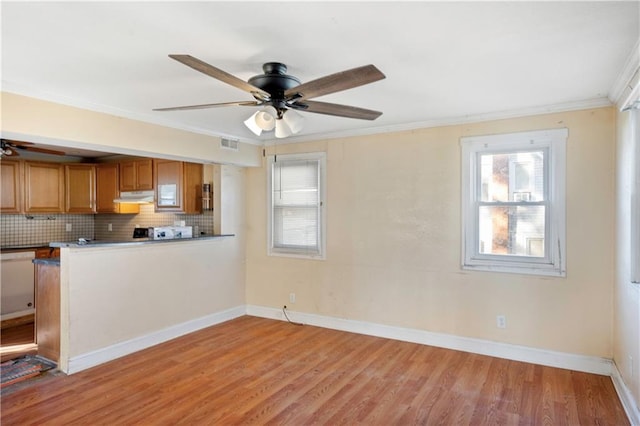 kitchen featuring ornamental molding, light wood-type flooring, white dishwasher, decorative backsplash, and ceiling fan