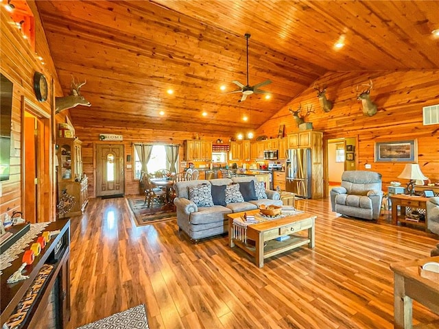 living room featuring ceiling fan, wooden walls, wood ceiling, and light wood-type flooring