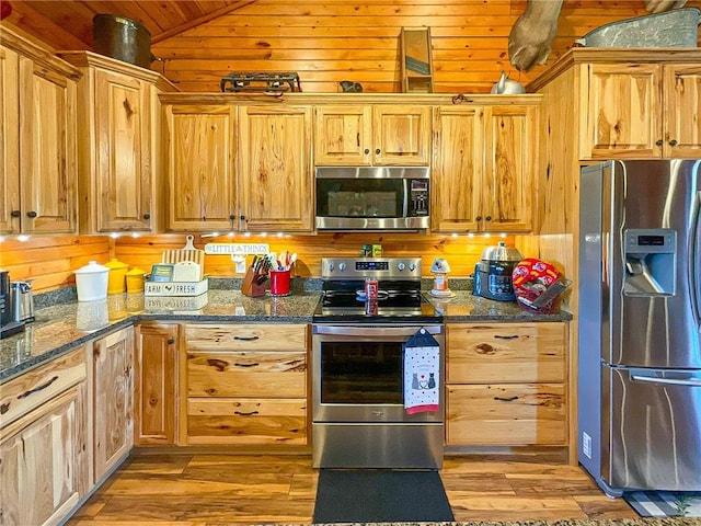 kitchen with dark stone countertops, light hardwood / wood-style floors, and appliances with stainless steel finishes