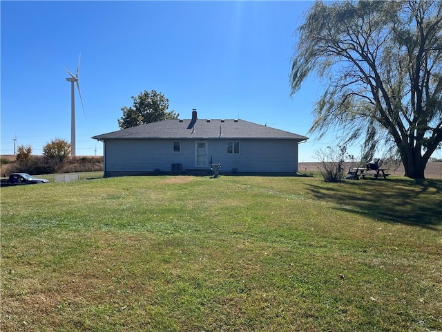 rear view of house featuring cooling unit and a lawn