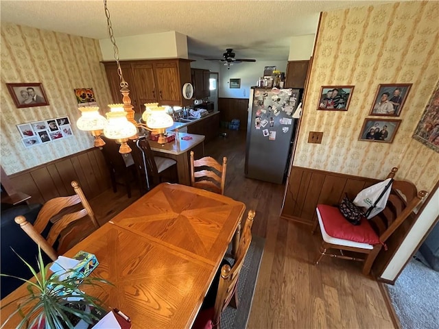 dining space featuring dark hardwood / wood-style floors, a textured ceiling, and ceiling fan with notable chandelier