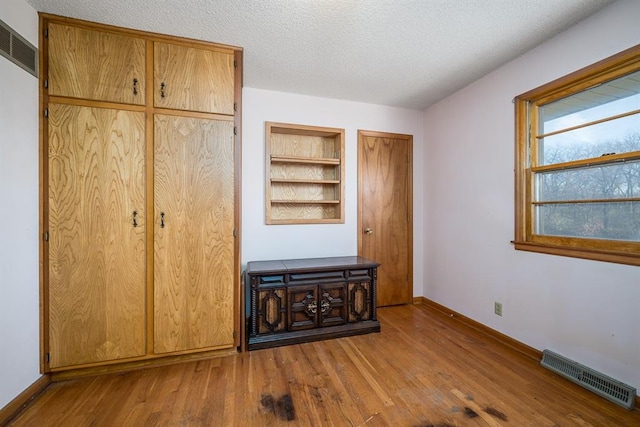 unfurnished bedroom featuring light wood-type flooring and a textured ceiling