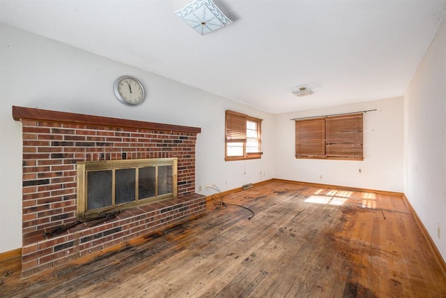 unfurnished living room with hardwood / wood-style floors and a brick fireplace