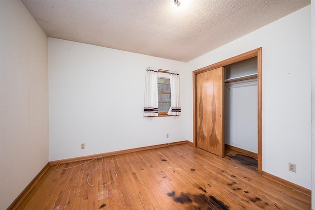 unfurnished bedroom with a textured ceiling, hardwood / wood-style flooring, and a closet