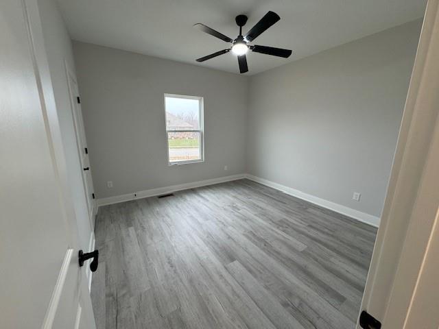 empty room with ceiling fan and light hardwood / wood-style flooring