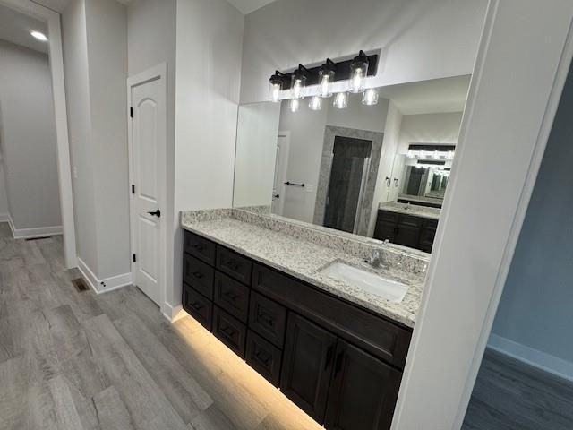 bathroom featuring a shower, hardwood / wood-style floors, and vanity