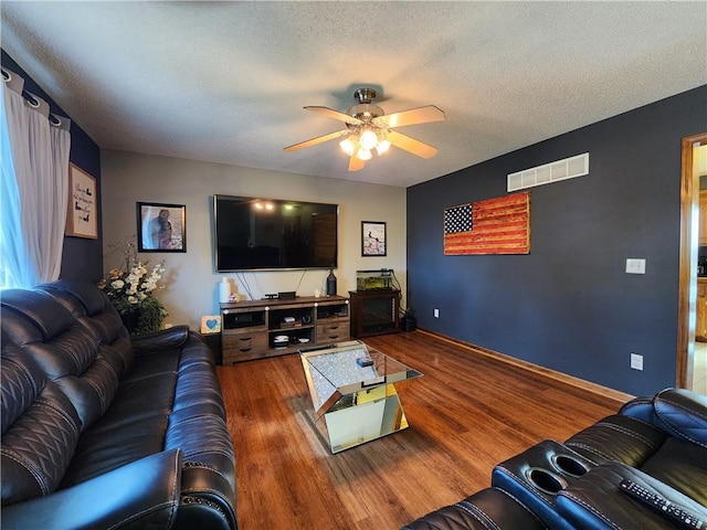 living room with ceiling fan, hardwood / wood-style floors, and a textured ceiling