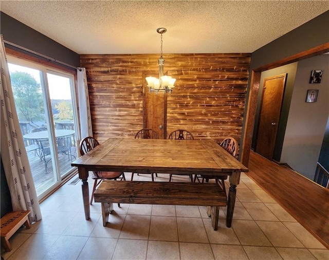 dining room featuring a notable chandelier, wooden walls, and a textured ceiling