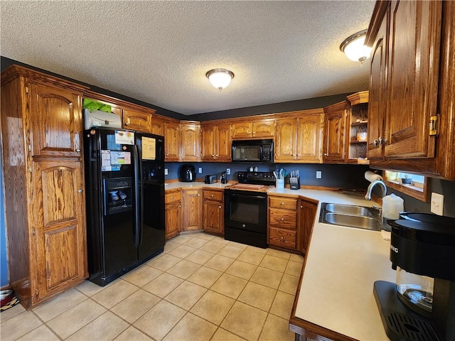 kitchen with sink, light tile patterned floors, a textured ceiling, and black appliances