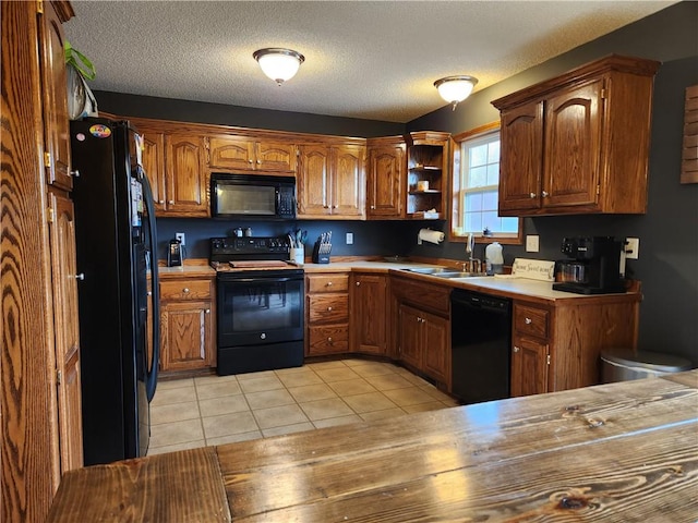 kitchen with light tile patterned flooring, sink, a textured ceiling, and black appliances