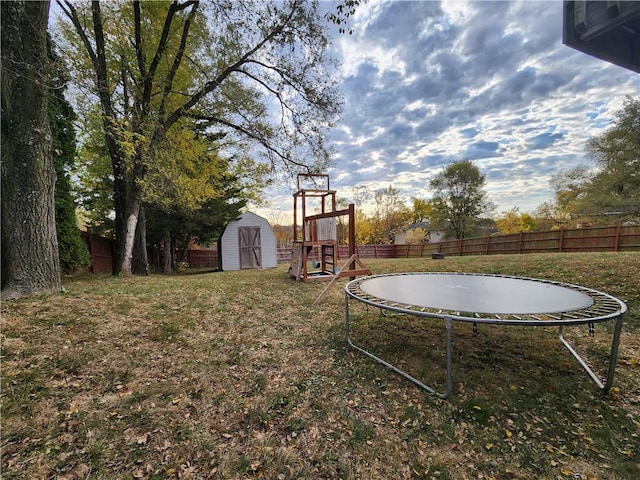 view of yard with a trampoline, a playground, and a storage unit