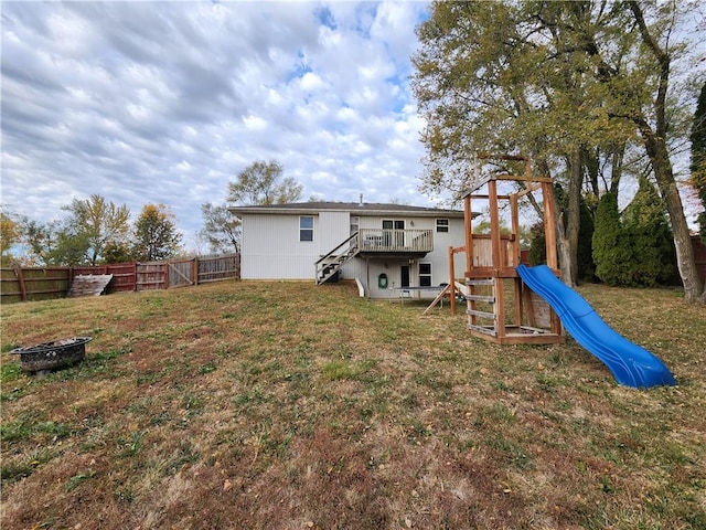 back of property featuring a playground, a lawn, and a fire pit