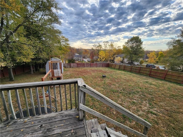 wooden terrace with a lawn, a playground, and a storage unit