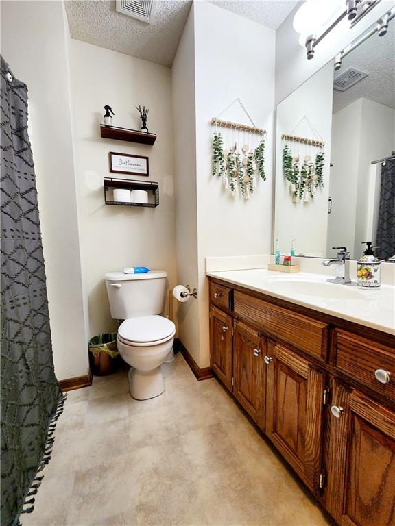 bathroom featuring vanity, a textured ceiling, and toilet