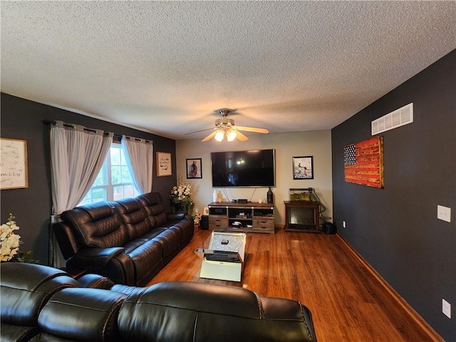 living room with ceiling fan, wood-type flooring, and a textured ceiling