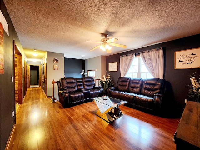 living room featuring wood-type flooring, a textured ceiling, and ceiling fan