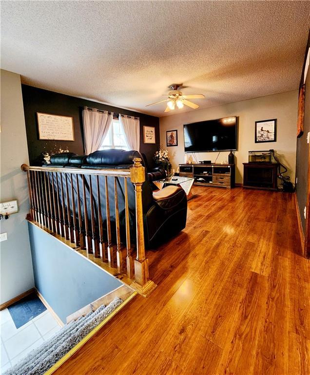 living room featuring hardwood / wood-style floors, a textured ceiling, and ceiling fan