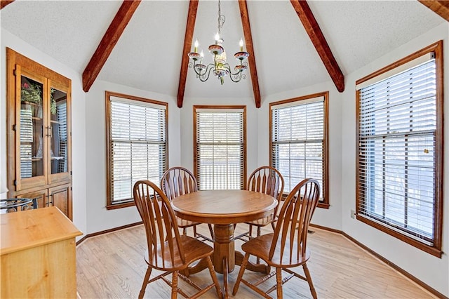 dining area with light hardwood / wood-style flooring, lofted ceiling with beams, and a notable chandelier