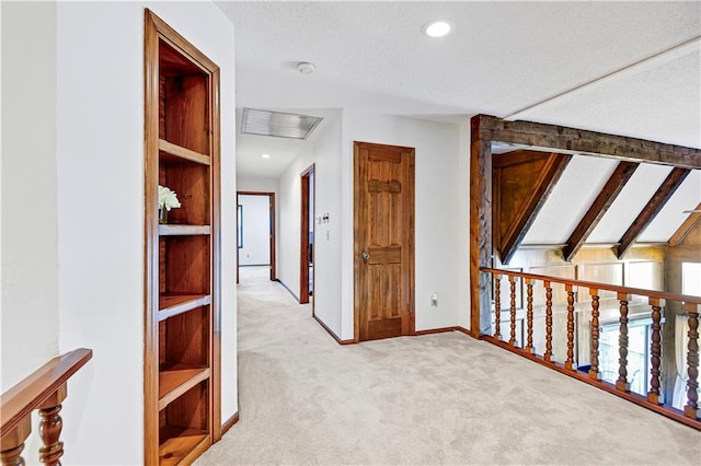 hallway featuring a textured ceiling, vaulted ceiling with beams, and light colored carpet