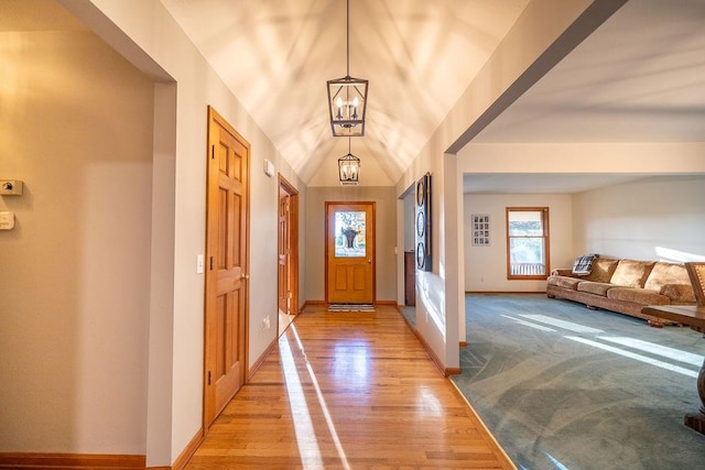 entryway featuring a notable chandelier, vaulted ceiling, and light hardwood / wood-style flooring