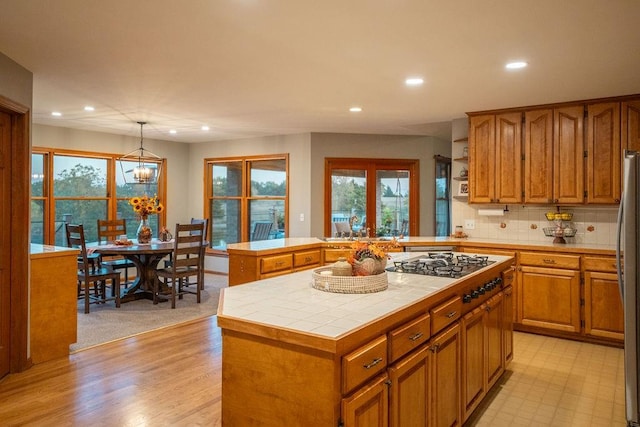 kitchen with a kitchen island, tile counters, decorative light fixtures, a chandelier, and tasteful backsplash